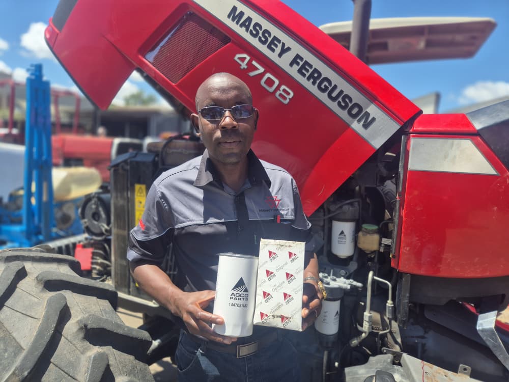 Farmec technician holding genuine AGCO parts beside a Massey Ferguson tractor